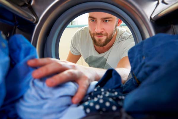 homem tirando roupas da secadora